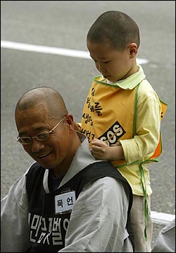 2003년 5월, 삼보일배 중 쉬고 있는 수경스님의 어깨를 한 어린이가 주물러 주고 있다.
